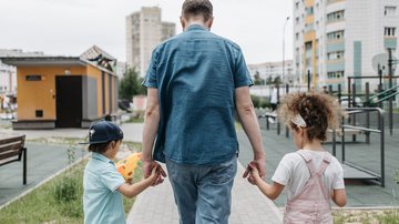 Pai caminhando de mãos dadas com seus filhos