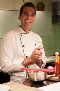 Imagem de Felipe Bellim sorrindo com uma roupa branca de chef