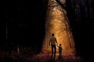 Imagem de um pai de mão dada com o filho em uma floresta 