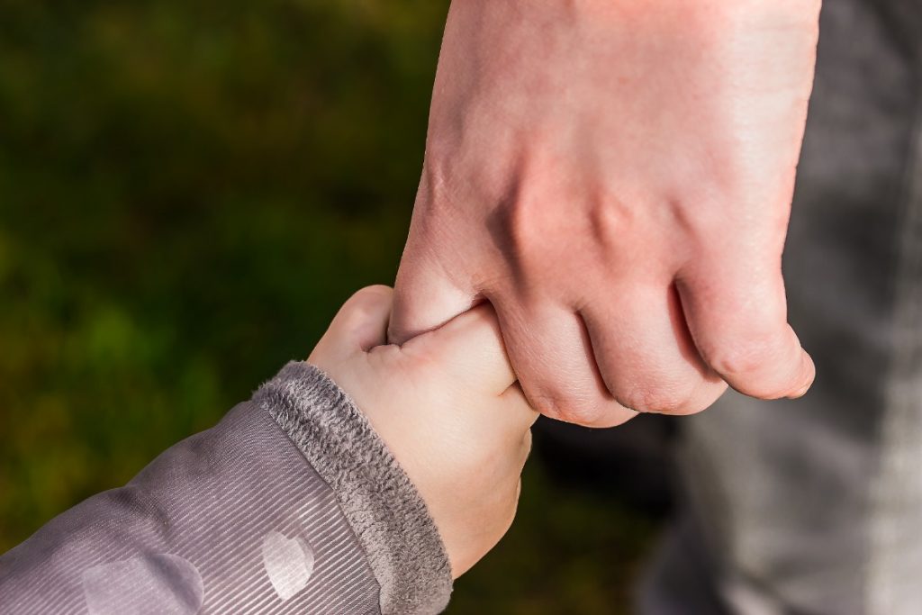 Mão de criança segurando uma mão de um adulto